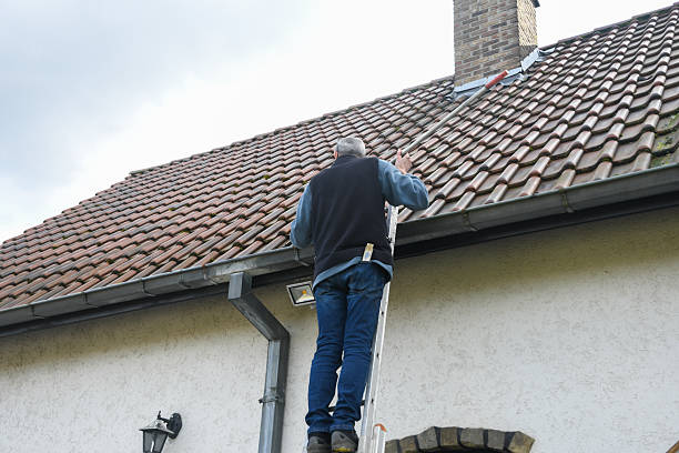 Dakdekker inspecteert een pannendak vanaf een ladder.